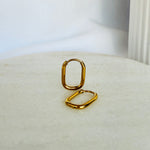 Load image into Gallery viewer, Pair of gold oval hoop earrings displayed on a neutral background
