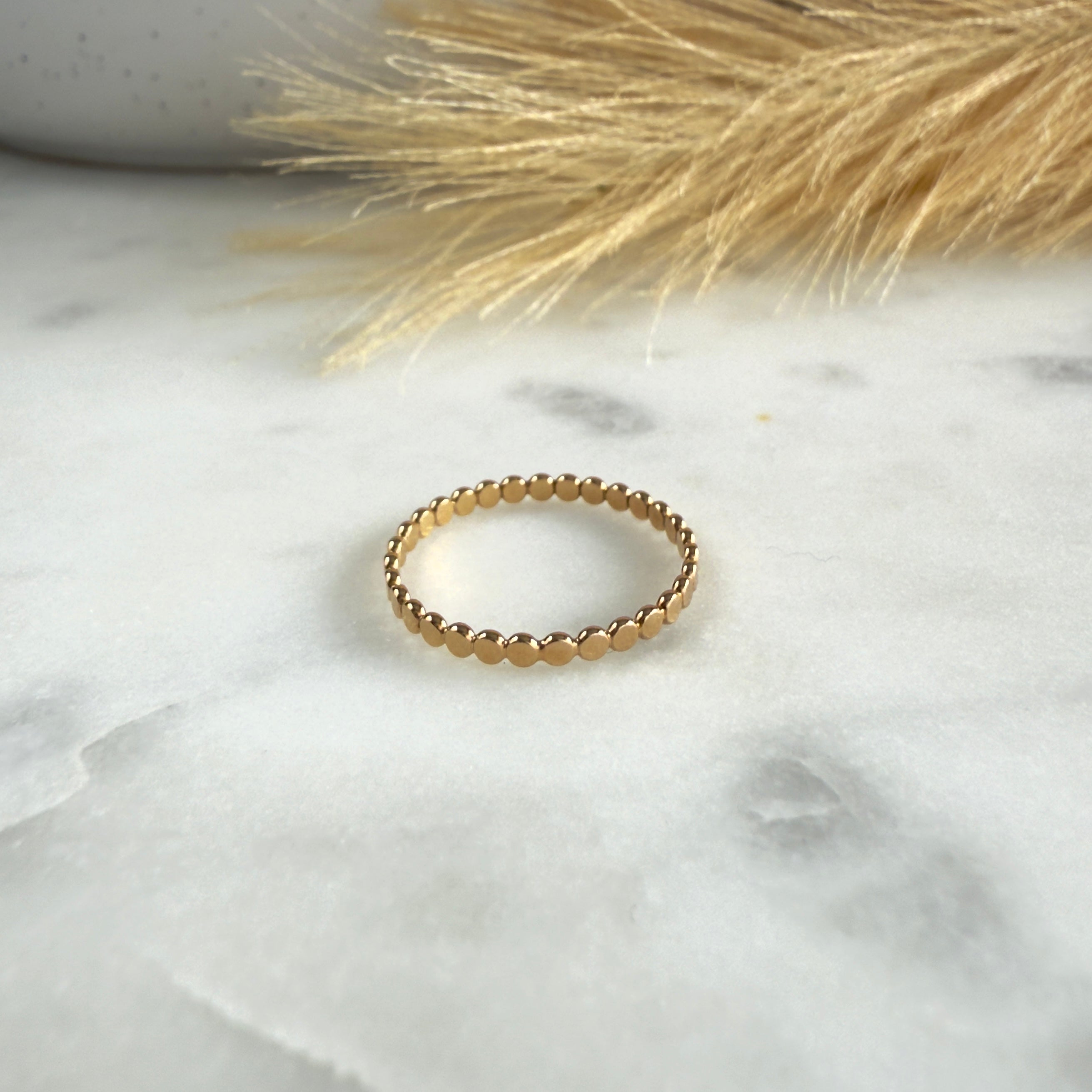 Gold ring on a marble surface with dried grass