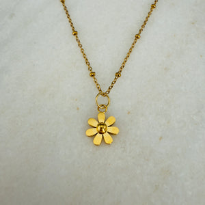 Gold flower pendant necklace on a light gray background