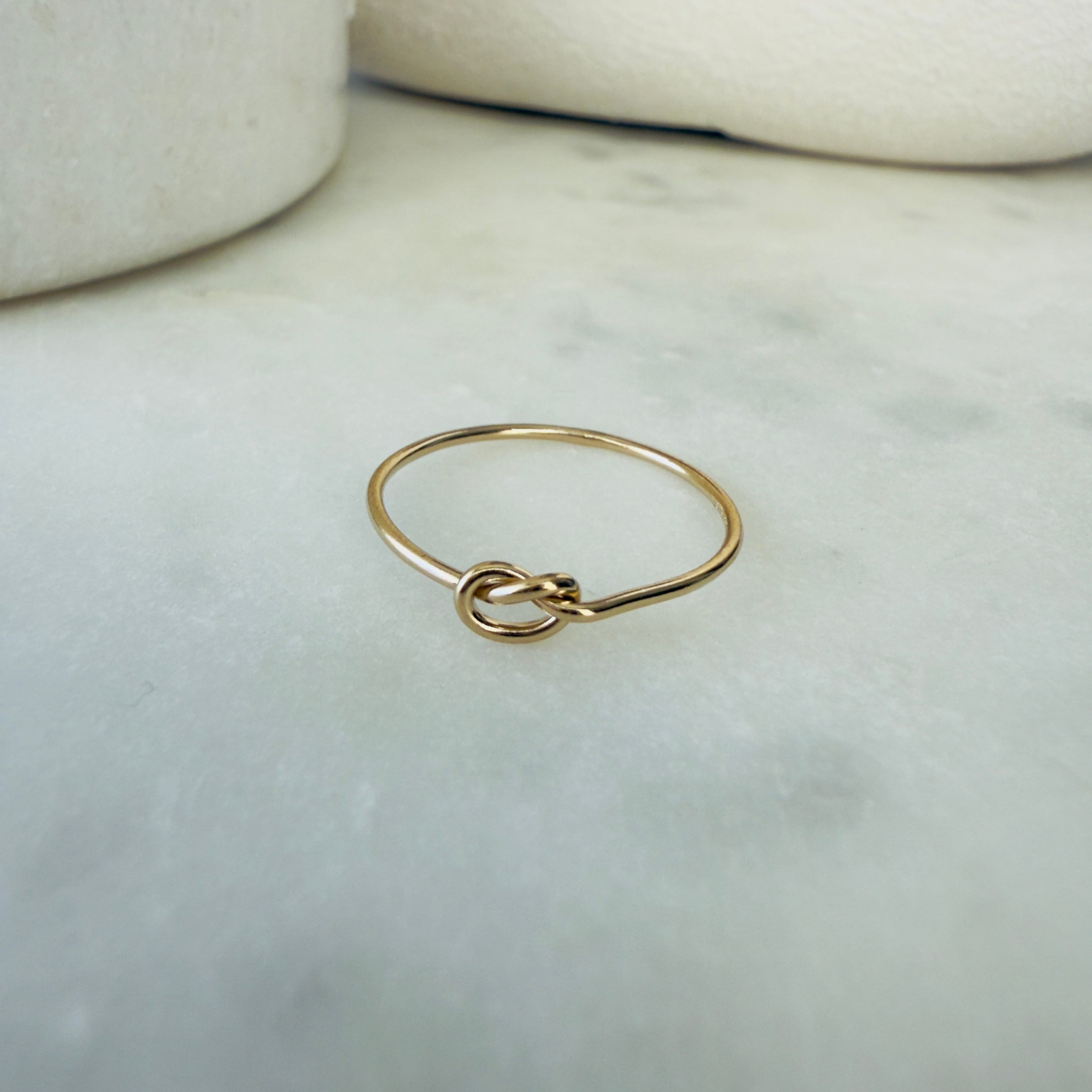 Gold ring with a knot design on a marble surface