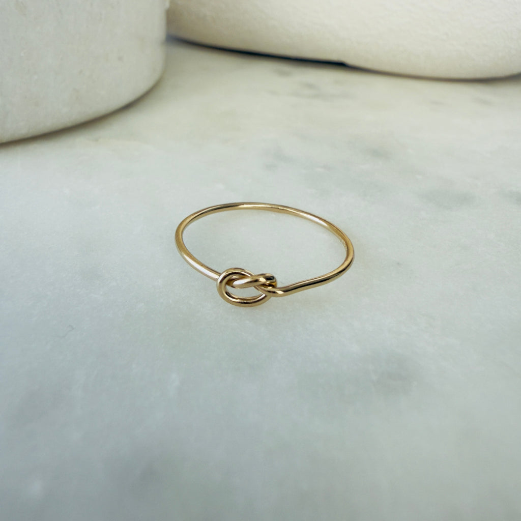 Gold ring with a knot design on a marble surface