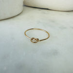 Load image into Gallery viewer, Gold ring with a knot design on a marble surface
