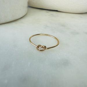 Gold ring with a knot design on a marble surface