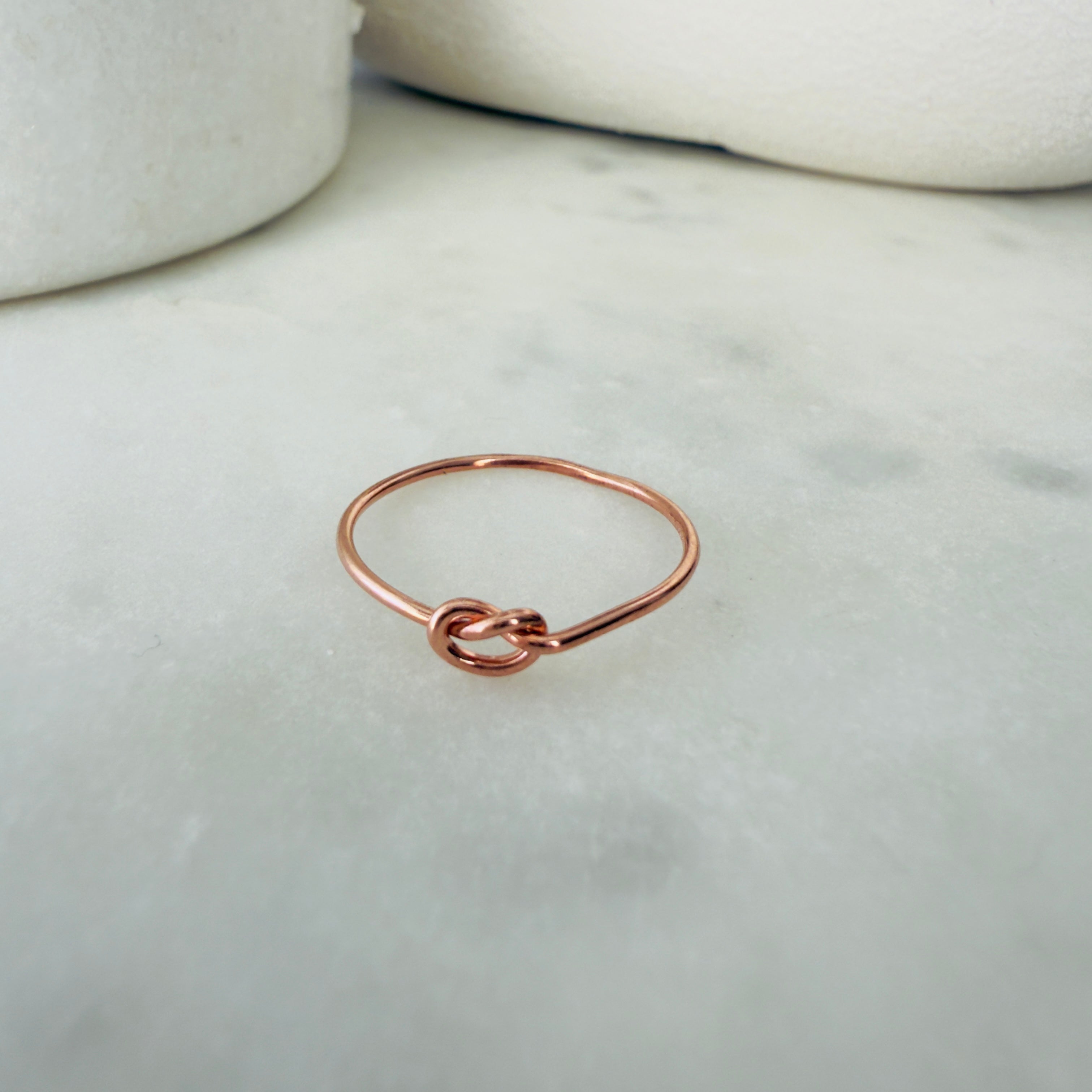 Rose gold knot ring on a marble surface