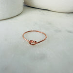 Load image into Gallery viewer, Rose gold knot ring on a marble surface
