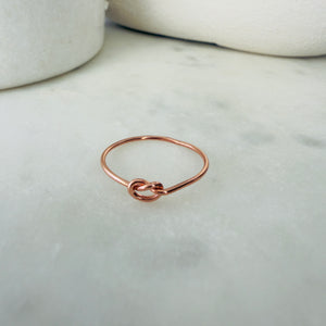 Rose gold knot ring on a marble surface