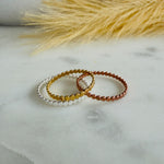 Load image into Gallery viewer, Three circles rings in silver, gold, and bronze on a marble surface with dried grass in the background.
