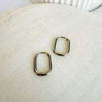 Load image into Gallery viewer, Pair of silver oval hoop earrings displayed on a neutral background
