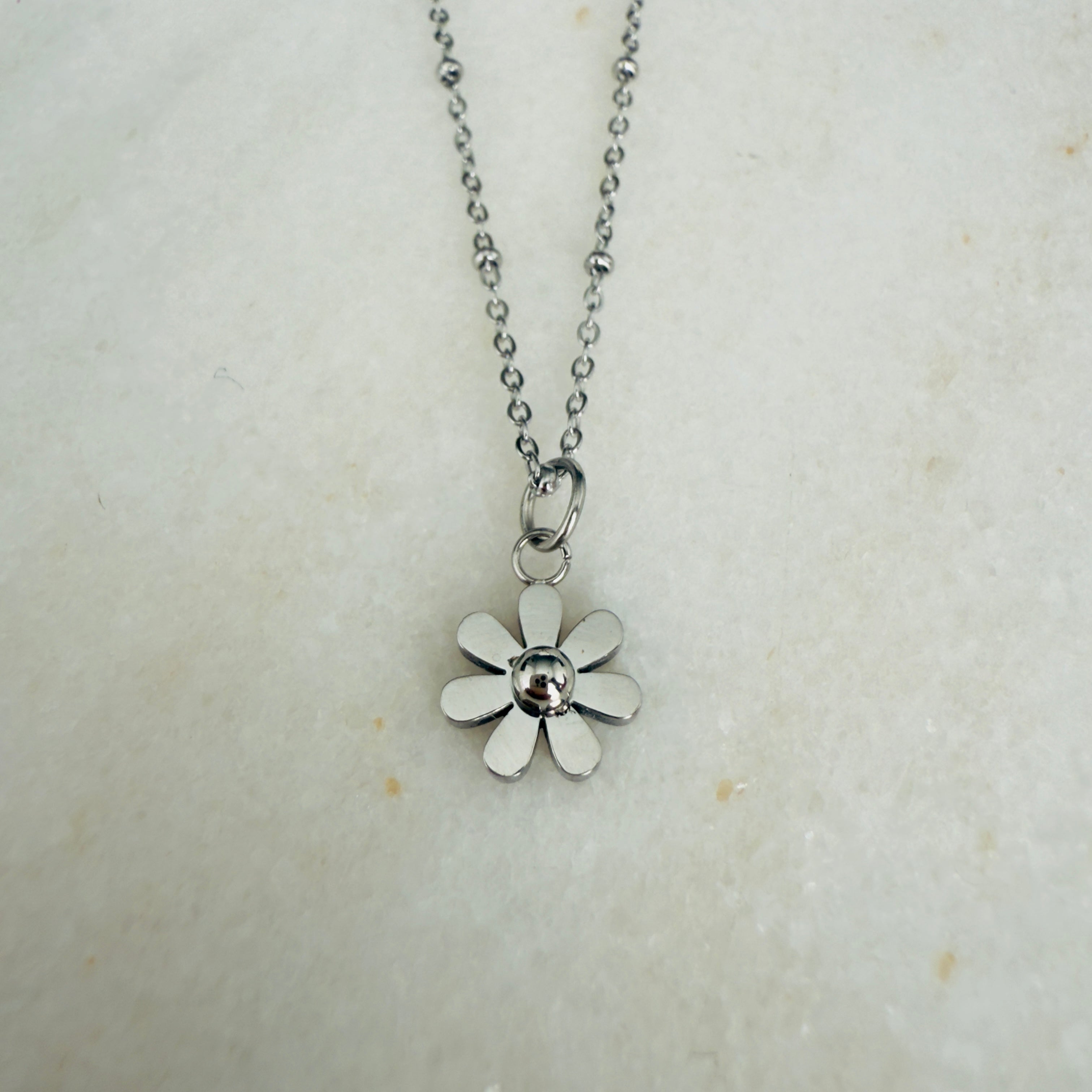 Silver flower pendant necklace on a light background