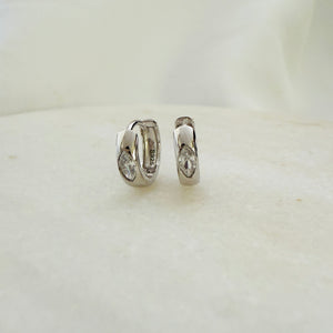 A pair of silver hoop earrings with cubic zirconia stones, displayed on a white surface.