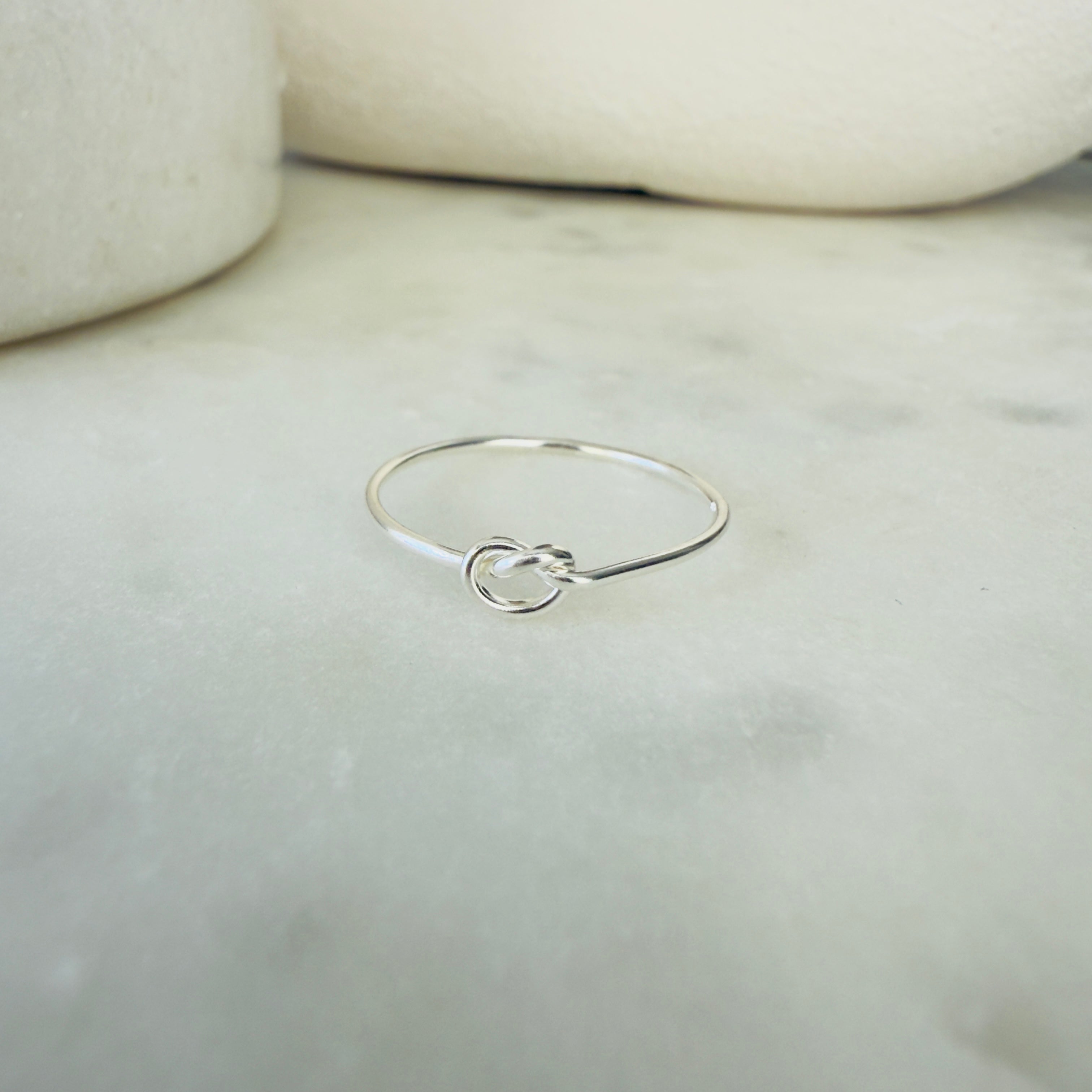 Silver ring with a knot design on a marble surface