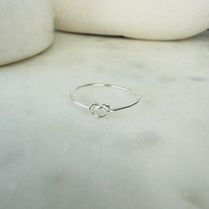 Silver ring with a knot design on a marble surface
