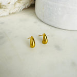 Load image into Gallery viewer, Gold teardrop stud earrings on a light marble surface with a white ceramic dish in the background.
