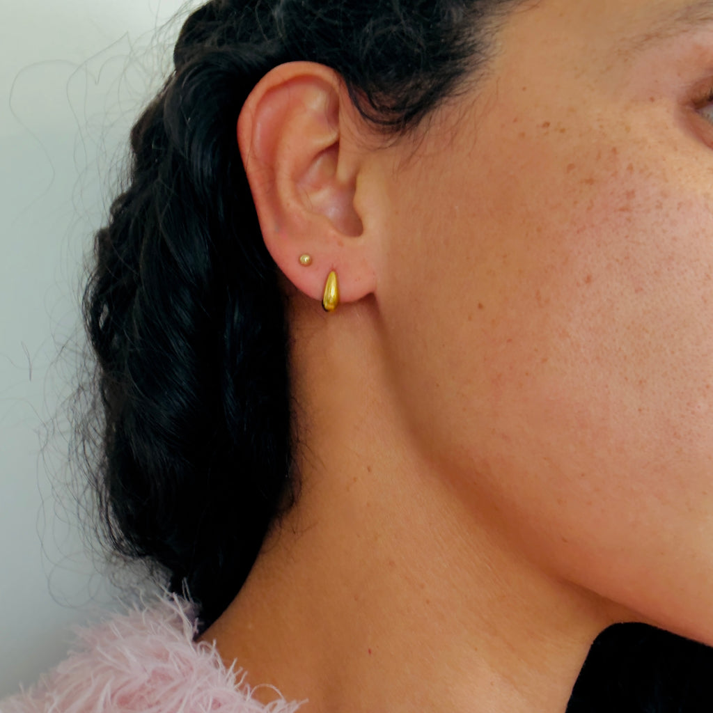 model wearing gold teardrop studs