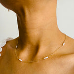Load image into Gallery viewer, Close-up of a woman wearing a gold filled trio pearl necklace, featuring groups of  three dainty freshwater pearls evenly spaced along a fine gold chain
