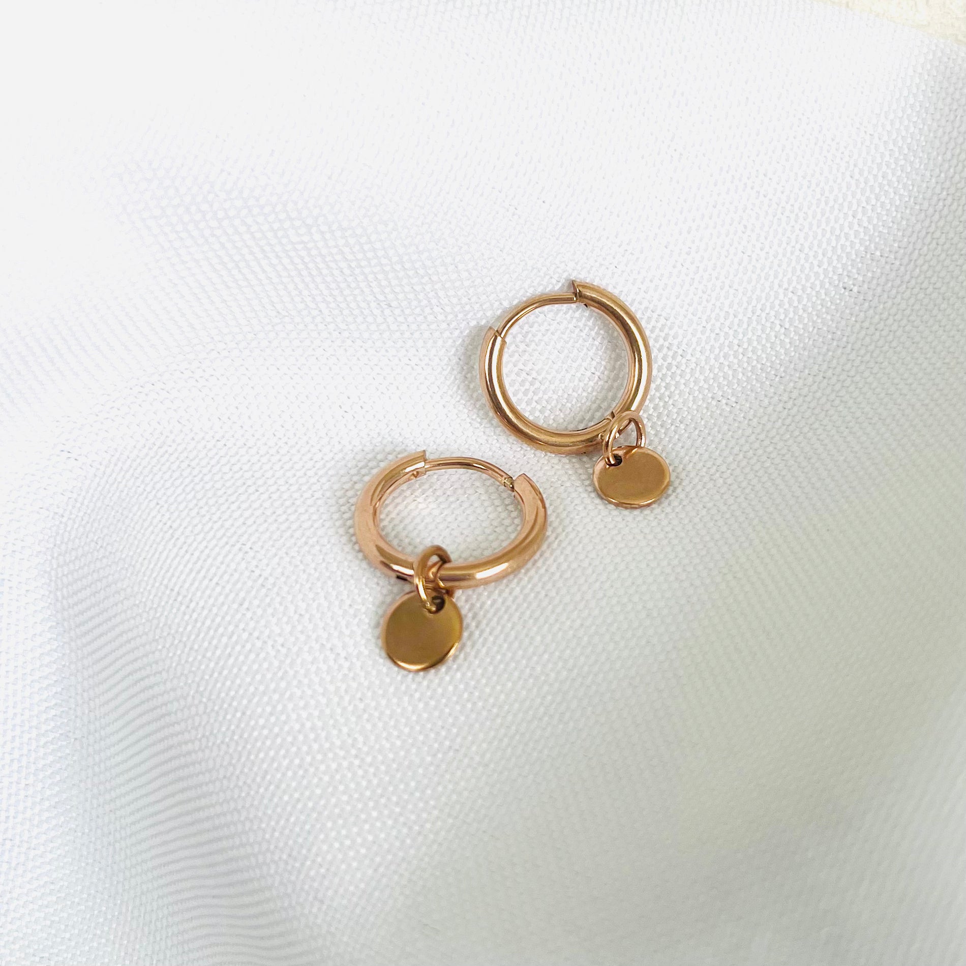 rose gold hoops with a small round tag charm